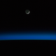 Illustration for article titled A Crescent Moon Above a Darkened Planet